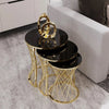 Set of black nesting tables with gold metal bases in a living room setting.
