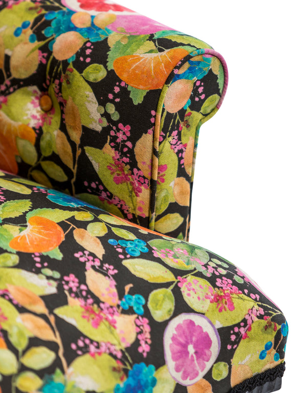 Close up of lemon and orange citrus print upholstery fabric on button back chair